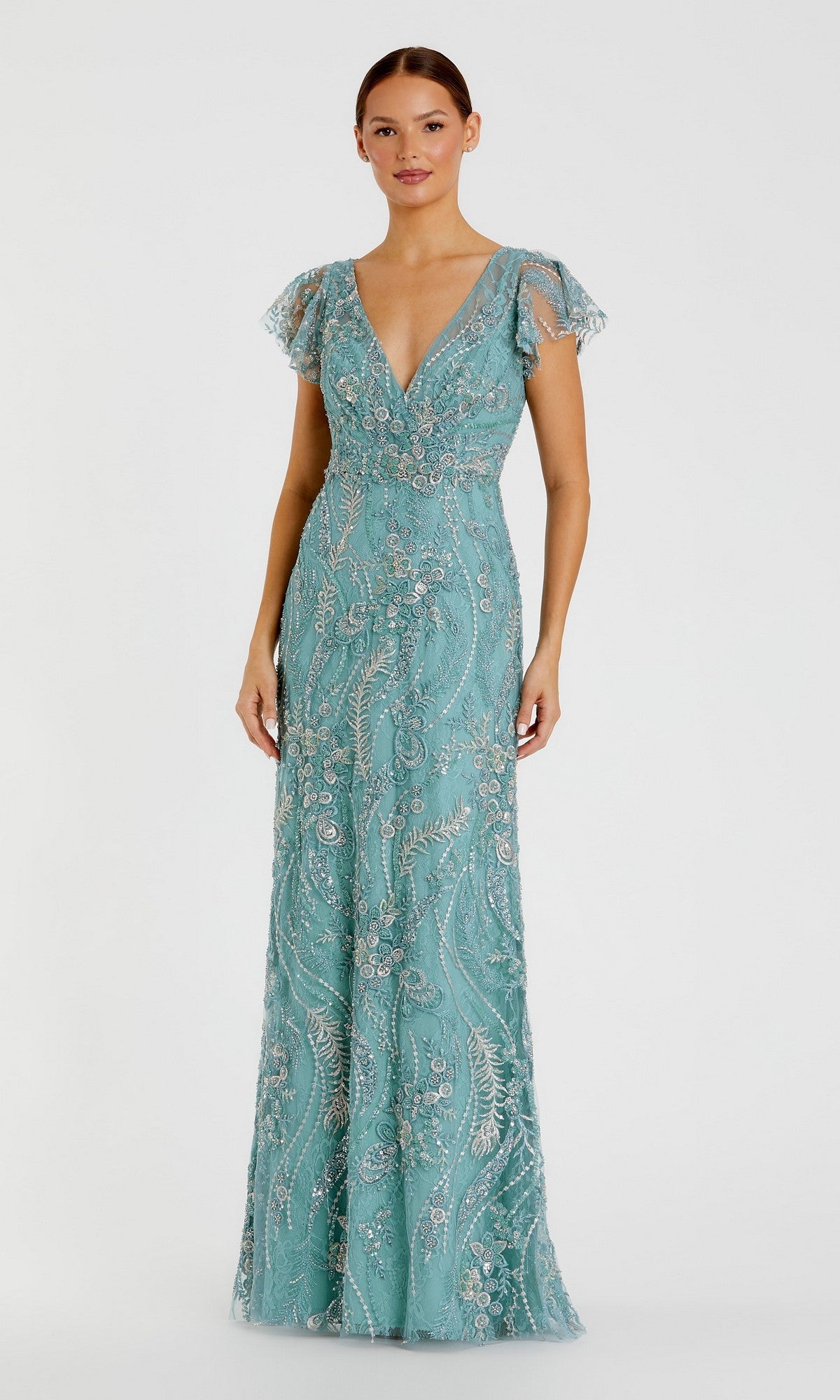 A woman wearing the Mac Duggal 68914 Long Formal Dress in seafoam, featuring short sheer sleeves, a deep V-neckline, and intricate shimmering beadwork. The floor-length gown exudes timeless sophistication and elegance against a plain light background.